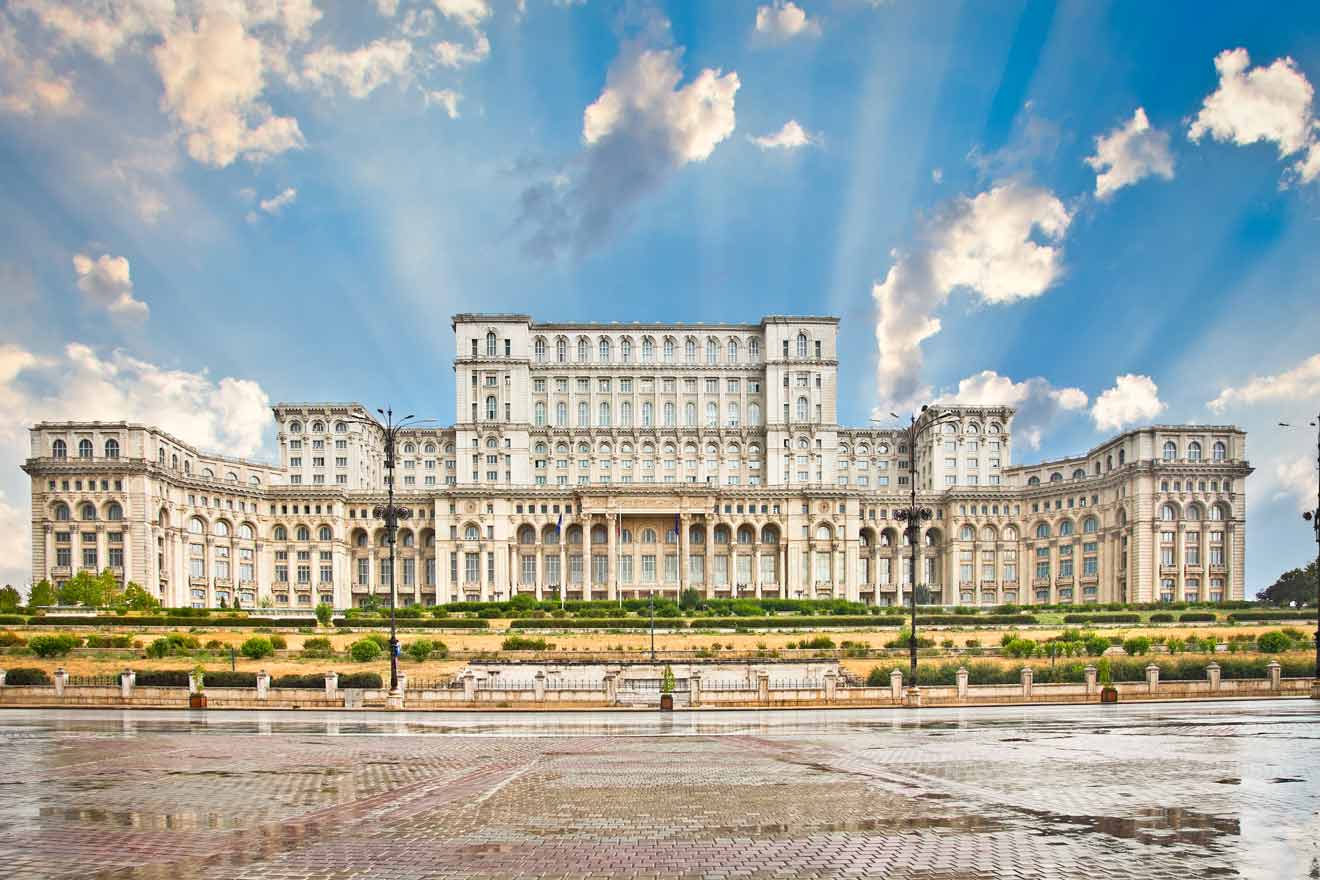 The Palace of the Parliament in Bucharest, Romania, under a dramatic sky with sunbeams shining through the clouds, highlighting the grandeur of this massive, imposing government building