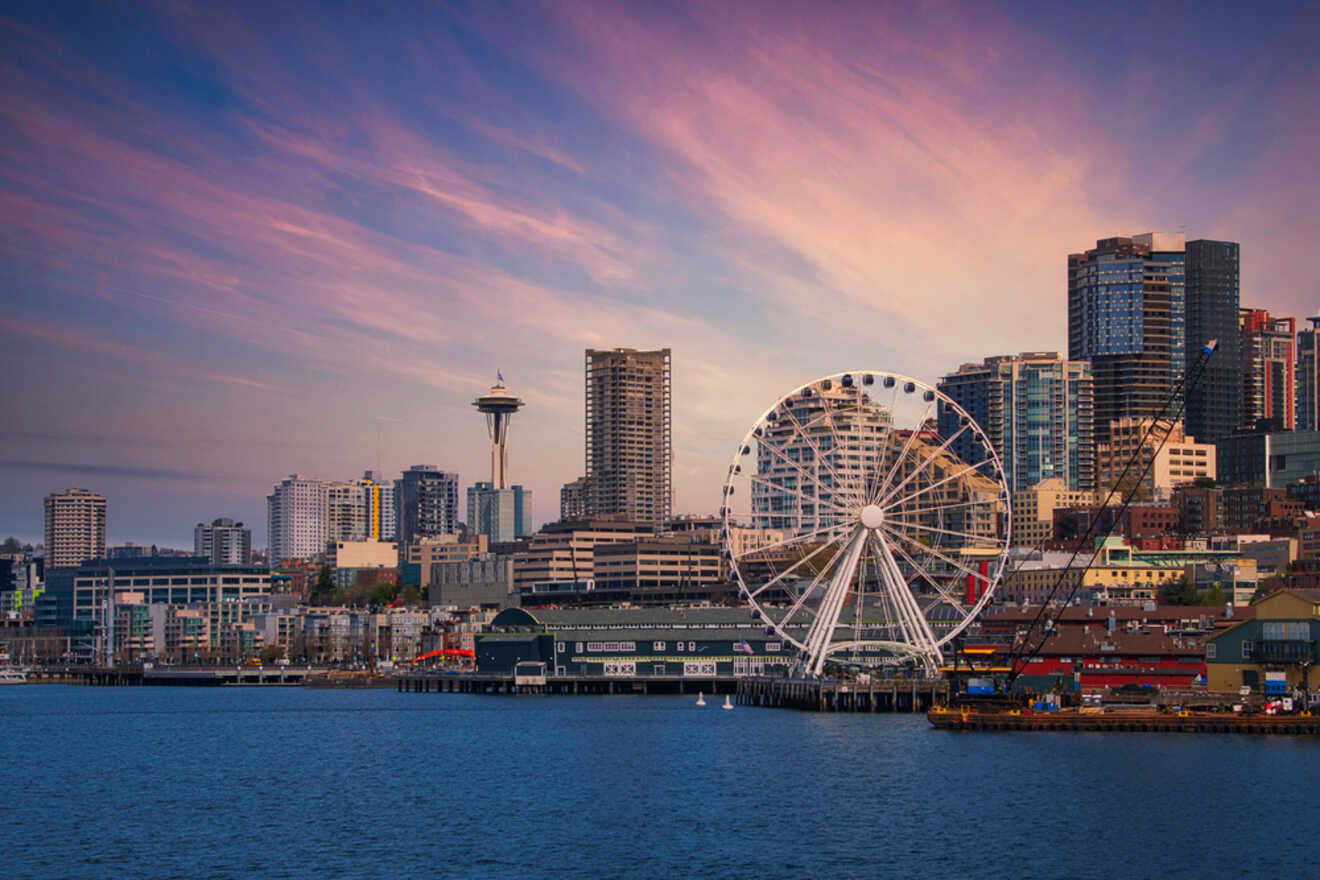 Seattle's downtown waterfront at sunset with the Great Wheel and skyscrapers against a pink-hued sky