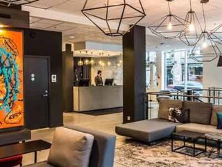 Modern hotel lobby with abstract art, stylish geometric lighting fixtures, and a neutral color scheme, offering a sleek welcome area for guests.