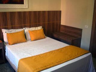 Hotel Diplomata's inviting double bed with wooden headboard and vibrant orange accents in a cozy, well-lit room
