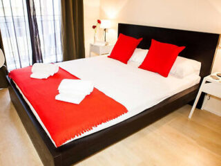 Elegant bedroom with a large bed, crisp white bedding, and bold red accents