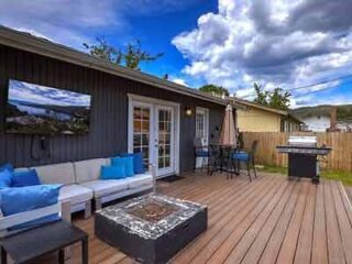 Cozy backyard patio with a fire pit table, L-shaped outdoor couch, and a barbecue grill, perfect for entertaining.