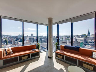 An urban apartment living space with large windows offering a panoramic view of the city skyline