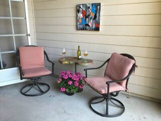 A cozy outdoor patio space with two pink cushioned swivel chairs and a small table