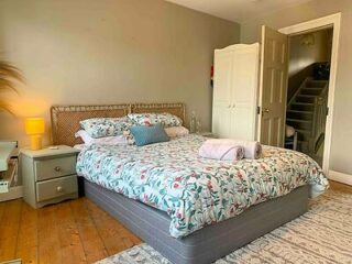 A cozy bedroom with a floral patterned comforter, wooden furniture, and soft ambient lighting