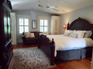 Elegant bedroom with a large wooden bed, plush bedding, seating area, and hardwood floors