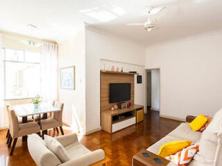 Bright and spacious living room with beige sofas, wooden floors, and minimalist decor in a Rio de Janeiro apartment