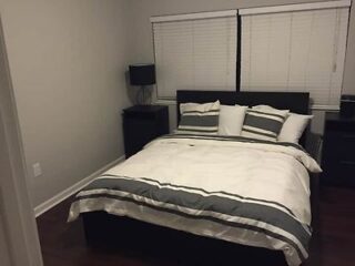 Bedroom with a dark wood queen bed with gray and white bedding, flanked by matching nightstands and lamps