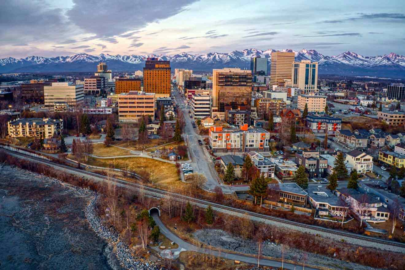 Aerial view of downtown Anchorage during twilight, with the city lights starting to shine against the backdrop of the Chugach Mountains.