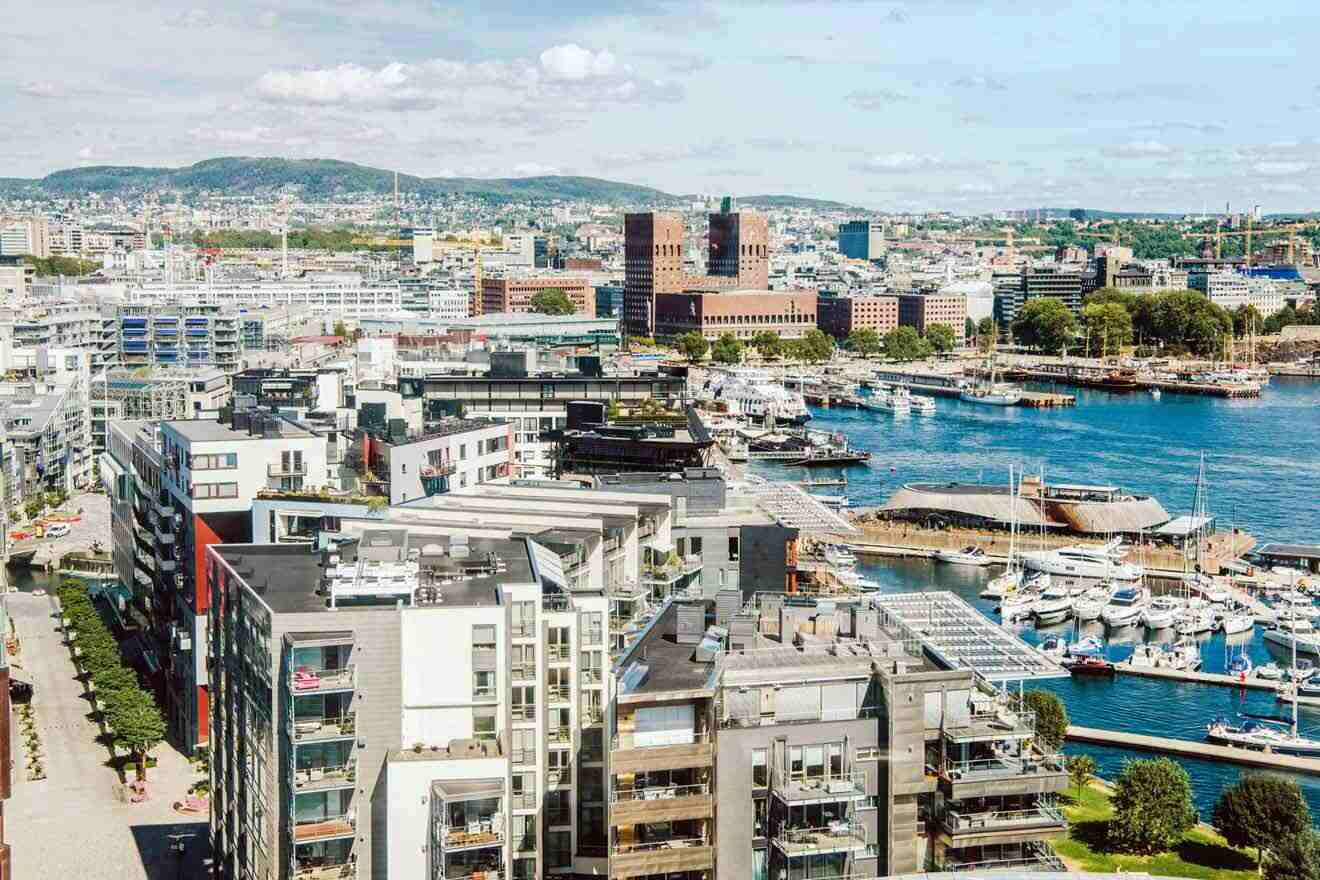 Elevated view of Oslo's waterfront architecture showcasing modern residential buildings and docked boats with the cityscape in the background.
