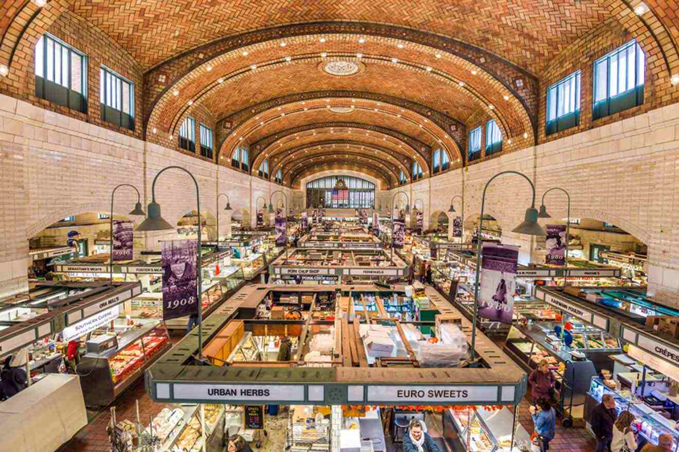 The bustling interior of a historic market hall with high arched ceilings, vendor stalls, and shoppers.