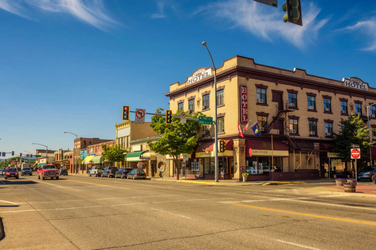 Historic downtown street view with a mix of modern and vintage storefronts, traffic lights, and vehicles under a clear blue sky