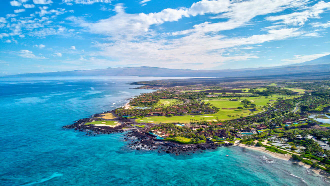 Breathtaking aerial view of the Kohala Coast's clear waters, resort accommodations, and golf courses