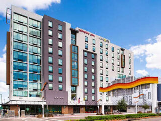 Exterior of a modern Hampton Inn hotel with a sleek design and colorful architectural elements