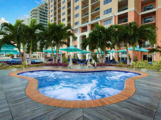 Inviting resort pool at Marriott's BeachPlace Towers with blue parasols, flanked by a wood deck and surrounded by high-rise buildings