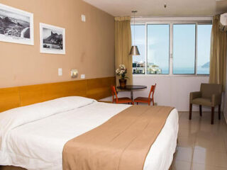 Comfortable hotel room with modern decor, a double bed, and a scenic window view of Rio de Janeiro's shoreline