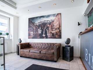 A chic hotel lobby with a classic leather couch, avant-garde art pieces, and a dramatic wall painting