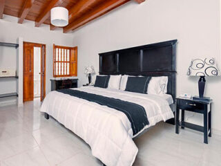 Luxurious bedroom with a large black headboard, crisp white bedding, and wooden ceiling beams
