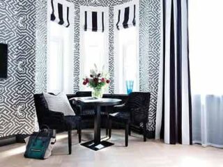 Elegant nook with black armchairs and a geometric-patterned wall, giving the space a chic and contemporary feel.