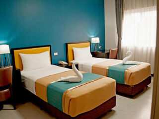 Bright twin bedroom with teal and orange bedding, modern lighting, and artwork on the walls