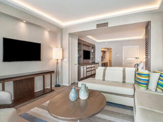 Elegant junior suite with a neutral-toned living area, contemporary furniture, and a seamless transition to the bedroom