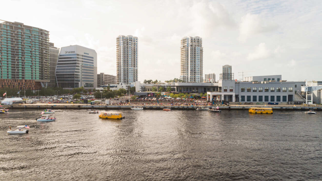 Waterfront view of the Tampa Riverwalk area with boats, high-rises, and a bustling crowd