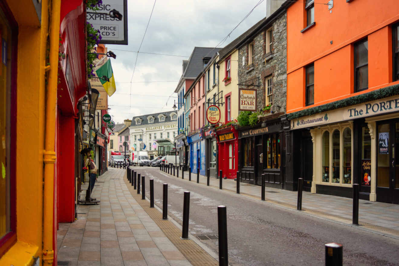 Vibrant Killarney street scene with colorful buildings, various shops, and a pedestrian path under a cloudy sky