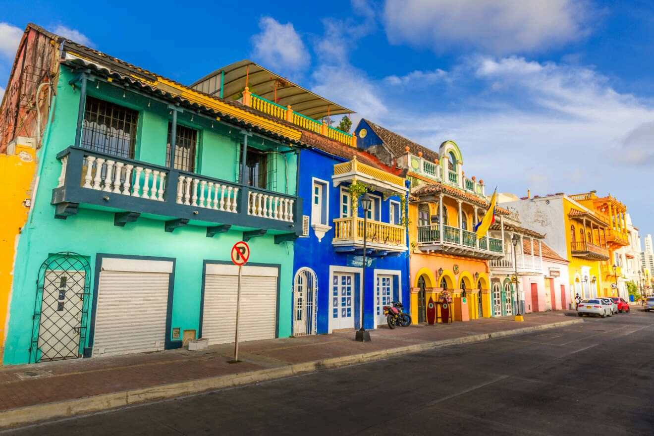 Historic Cartagena street lined with colorful buildings, featuring traditional balconies and vivid facades, showcasing the charm of Colombian architecture