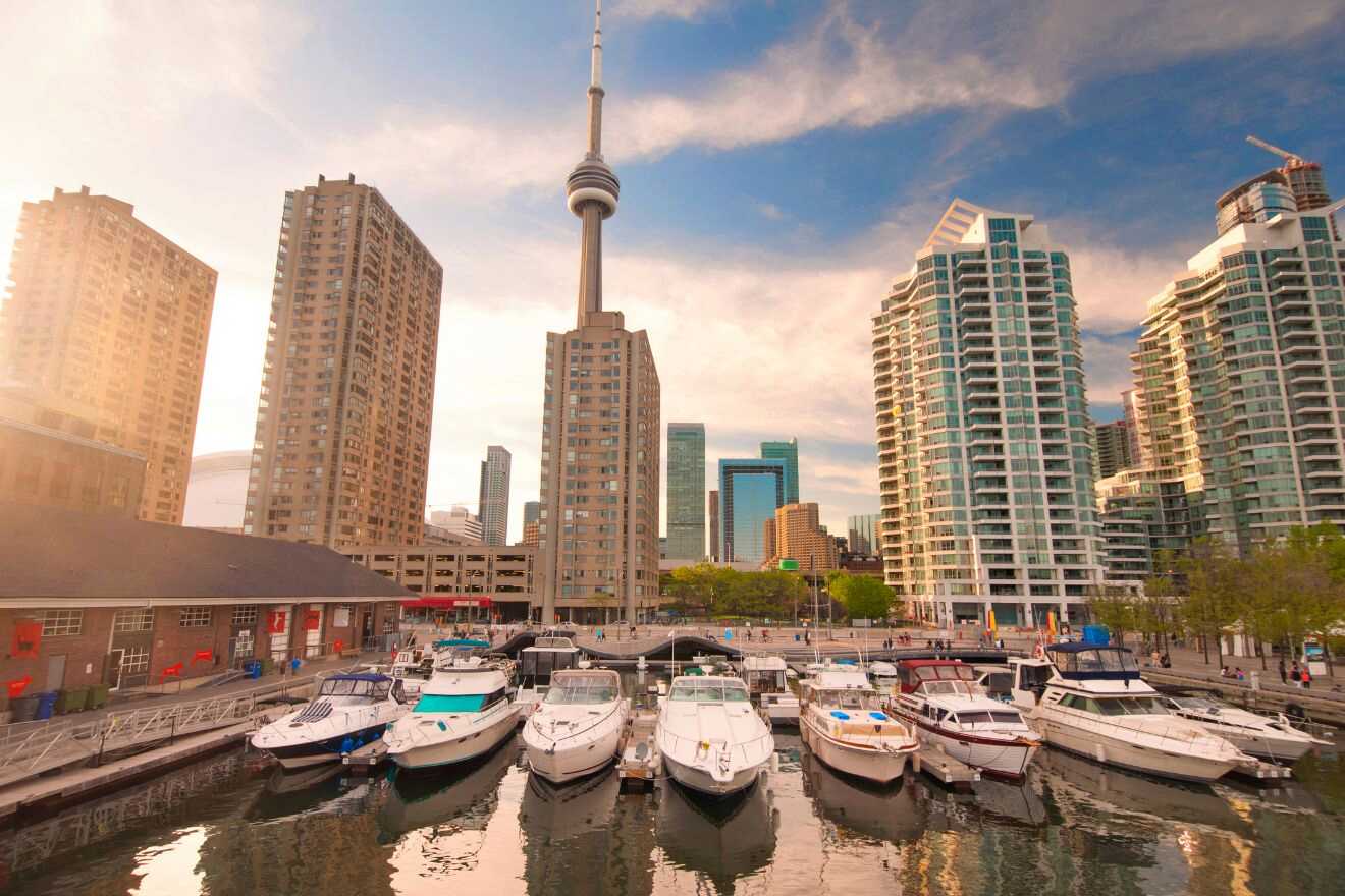 Tranquil Harborfront view at golden hour with boats moored in calm waters, the CN Tower rising above the Toronto skyline