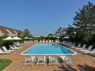 Sunny poolside area at Windward Shores with lounge chairs and umbrellas