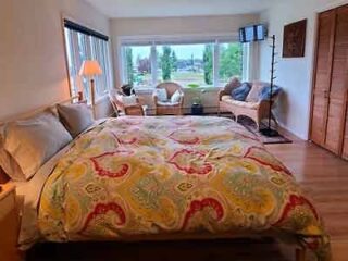 A bedroom with a colorful bedspread, a seating area by the window, and warm lighting, creating a cozy atmosphere.