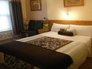 A simplistic hotel room with a large bed, brown accents, and a welcoming atmosphere