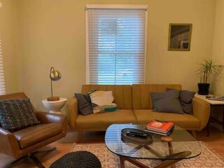 Mid-century modern living room with a mustard yellow sofa, leather chair, and a glass coffee table