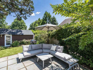 Charming outdoor patio of a Classic Hamptons Cottage with comfortable seating and an umbrella
