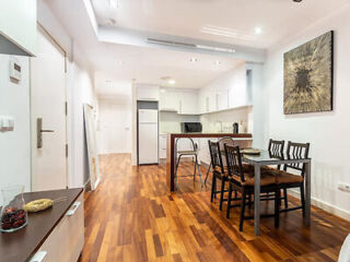 Sleek dining area in featuring hardwood floors, a modern kitchen, and contemporary artwork