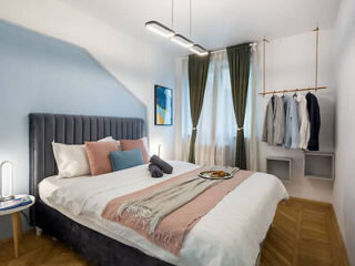 A compact yet stylish bedroom with a blue upholstered bed, chic decor, and smart storage solutions