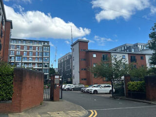 Manchester city street view on a sunny day with a mix of modern apartment buildings and a clear blue sky, showcasing the city's residential architecture