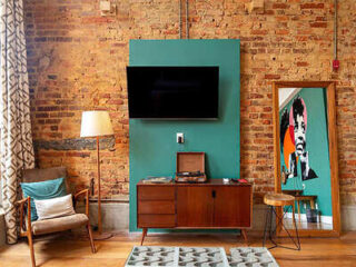 Eclectic living space with exposed brick walls, teal accents, and a large, flat-screen TV for a stylish stay in Rio