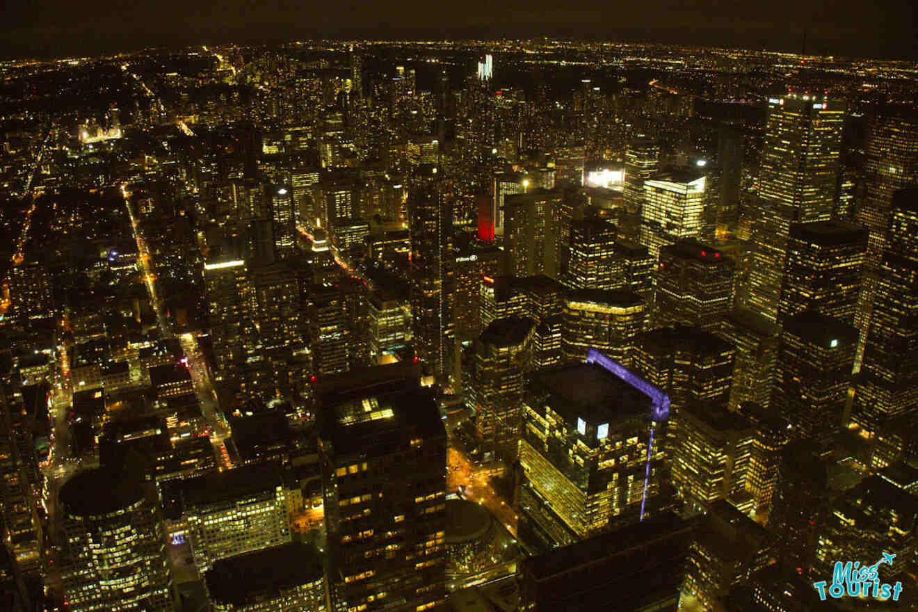 A night view of Toronto's dense skyline illuminated with various colors, showcasing the urban density and vibrancy of the city