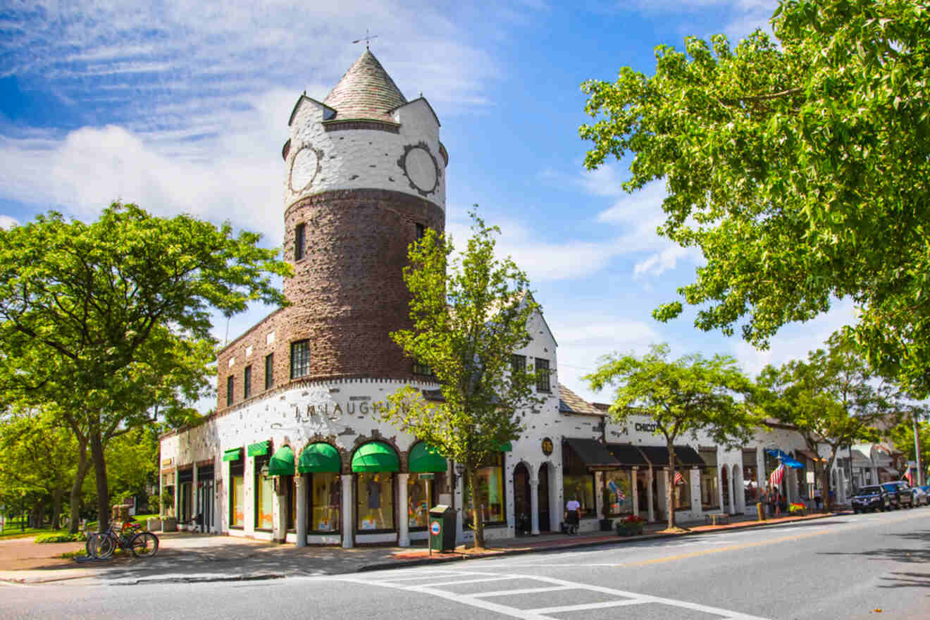 A distinctive building with a clock tower in Southampton, lined with shops and lush trees, showcasing the luxury and charm of Southampton in the Hamptons