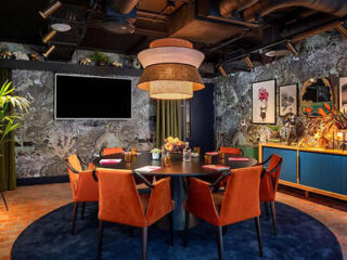 Eclectic dining space in a boutique hotel with vibrant wallpaper, velvet chairs, and artistic decor