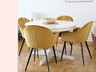 A modern dining area with mustard yellow velvet chairs and a white round table on a herringbone parquet floor