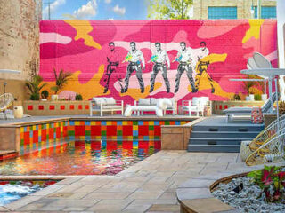 A lively outdoor hotel pool area with a colorful and artistic backdrop