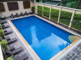 Hotel pool area with blue lounge chairs, a large swimming pool, and surrounding greenery