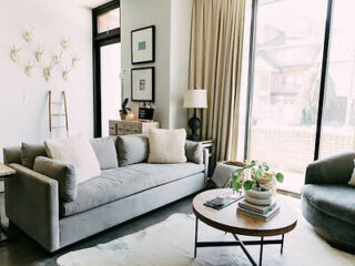 An elegantly decorated living room with a large sofa, chic decor, and ample natural light