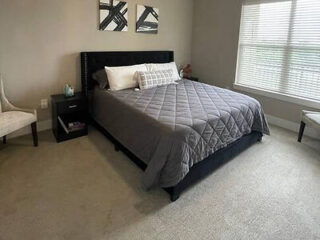 Contemporary bedroom with a king-size bed with a dark headboard, gray bedding, and white walls with minimalist decor