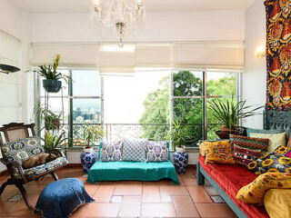 Colorful and artistic living area with vibrant textiles, lush plants, and ample natural light