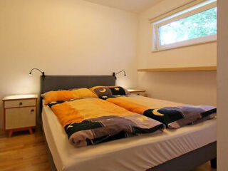 A minimalistic hotel room with a comfortable bed, simple furnishings, and a window