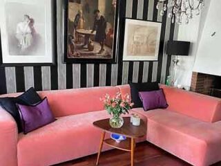 Chic living room with a salmon pink corner couch, wooden coffee table, and framed artwork creating an elegant, vintage atmosphere.