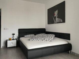 A stylish bedroom with a minimalist design, featuring a large bed with chic black and white bedding, a contemporary art piece on the wall